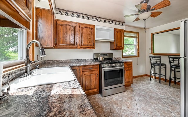 2760 Ridge Road Ext, Economy, PA 15005 - kitchen with stainless steel range with gas stovetop, a sink, brown cabinets, light tile patterned flooring, and a ceiling fan