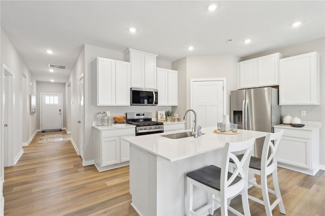 3045 Audrey Dr, Hempfield Twp Wml, PA 15601 - kitchen with appliances with stainless steel finishes, a sink, a kitchen bar, a kitchen island with sink, and light wood-type flooring
