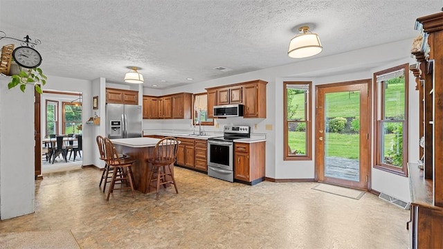 201 Clarke Rd, Buffalo Twp Wsh, PA 15323 - kitchen featuring stainless steel appliances, a kitchen breakfast bar, light countertops, baseboards, and a textured ceiling