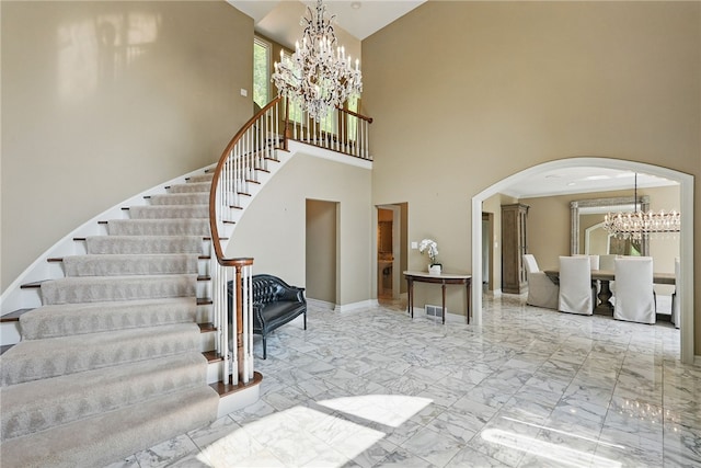 559 Normandy Ct, Fox Chapel, PA 15238 - staircase with a chandelier, arched walkways, a towering ceiling, marble finish flooring, and baseboards