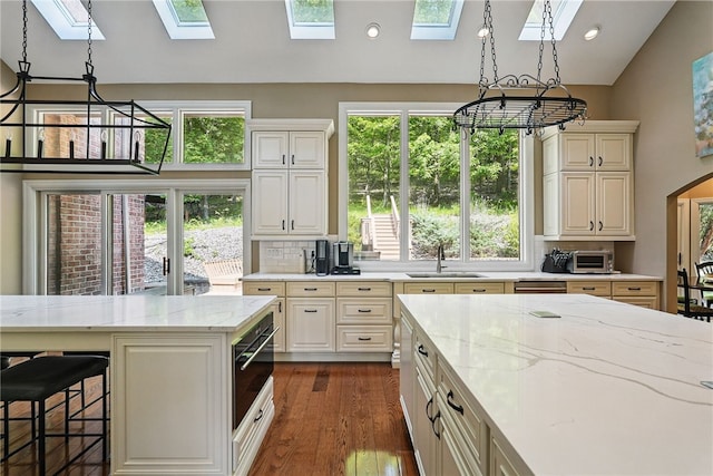 559 Normandy Ct, Fox Chapel, PA 15238 - kitchen featuring a skylight, a sink, vaulted ceiling, decorative backsplash, and recessed lighting
