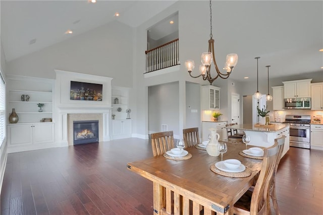 109 Summer Ln, Mount Pleasant Twp Was, PA 15057 - dining room featuring dark wood-style flooring, high vaulted ceiling, a glass covered fireplace, built in shelves, and a chandelier