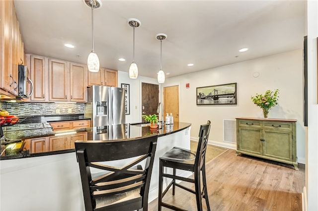 306 4th Ave Unit 902, Downtown Pgh, PA 15222 - kitchen with stainless steel appliances, dark countertops, backsplash, decorative light fixtures, and light wood-style flooring