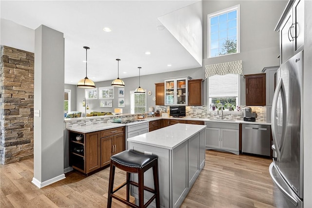 711 SE Simpson Howell, Elizabeth Twp/Boro, PA 15037 - kitchen featuring appliances with stainless steel finishes, a peninsula, light countertops, glass insert cabinets, and light wood-style flooring