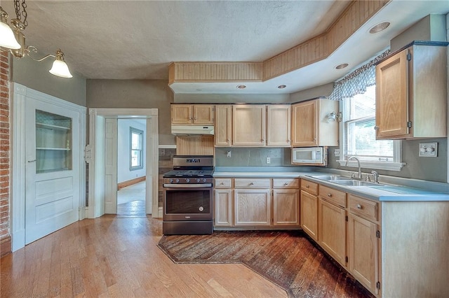 1457 Orator St, Crafton Heights, PA 15204 - kitchen featuring stainless steel range with gas stovetop, under cabinet range hood, light brown cabinetry, white microwave, and a textured ceiling