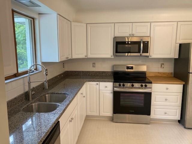 1014 State Rd, Monessen, PA 15062 - kitchen featuring appliances with stainless steel finishes, white cabinetry, dark stone countertops, and decorative backsplash