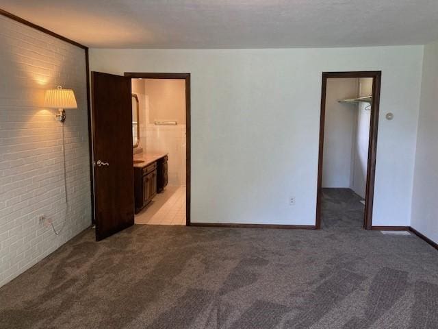 1014 State Rd, Monessen, PA 15062 - unfurnished bedroom featuring light colored carpet, brick wall, a walk in closet, ensuite bath, and a closet