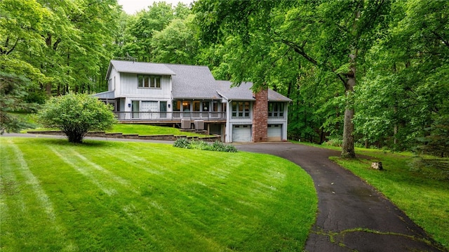 124 Oak Ln, Adams Twp, PA 16046 - view of front of home featuring asphalt driveway, a garage, a front yard, a chimney, and a wooded view