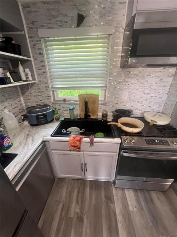 3539 York St, Munhall, PA 15120 - kitchen with stainless steel appliances, wood finished floors, tasteful backsplash, white cabinetry, and light countertops