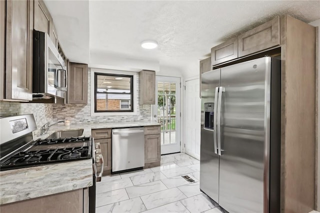 330 Delaney Dr, Wilkins Twp, PA 15235 - kitchen featuring stainless steel appliances, light marble finish flooring, decorative backsplash, a textured ceiling, and light stone counters