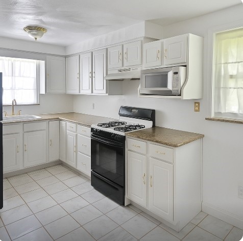 4717 Coleridge St, Stanton Heights, PA 15201 - kitchen featuring gas stove, white microwave, under cabinet range hood, and white cabinets