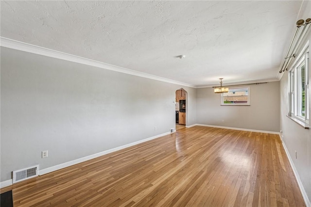 4100 Burnsire Dr, Hempfield Twp Wml, PA 15642 - unfurnished room with a chandelier, arched walkways, light wood-style flooring, ornamental molding, and a textured ceiling