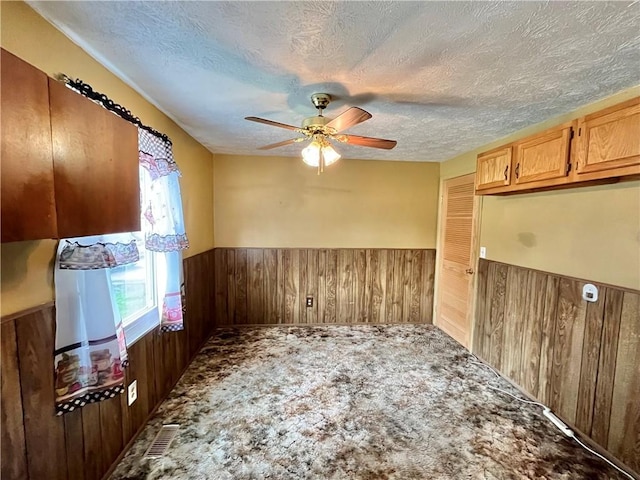 1974 Tara Dr, North Huntingdon, PA 15642 - unfurnished dining area featuring wood walls, a ceiling fan, a wainscoted wall, a textured ceiling, and carpet