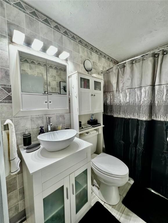 201 Esther Ave, New Kensington, PA 15068 - bathroom featuring tile walls, vanity, decorative backsplash, a shower with shower curtain, and a textured ceiling
