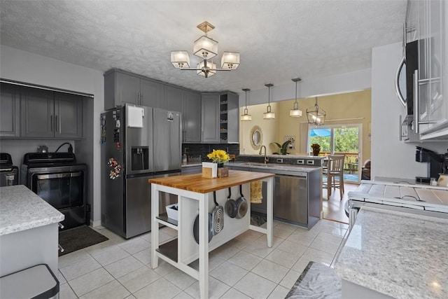 23 Sunset Ct, Cranberry Twp, PA 16066 - kitchen with stainless steel appliances, washing machine and clothes dryer, light tile patterned floors, a peninsula, and a chandelier