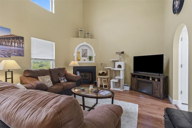 23 Sunset Ct, Cranberry Twp, PA 16066 - living room featuring healthy amount of natural light, a fireplace, wood finished floors, a towering ceiling, and arched walkways