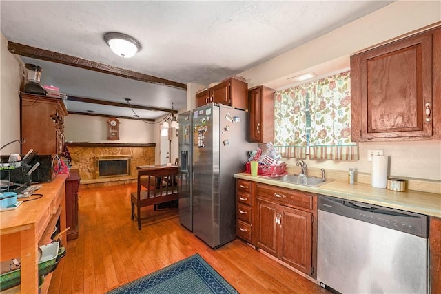 1260 6th St, Castle Shannon, PA 15234 - kitchen featuring appliances with stainless steel finishes, light wood-style flooring, a fireplace, brown cabinets, and beamed ceiling
