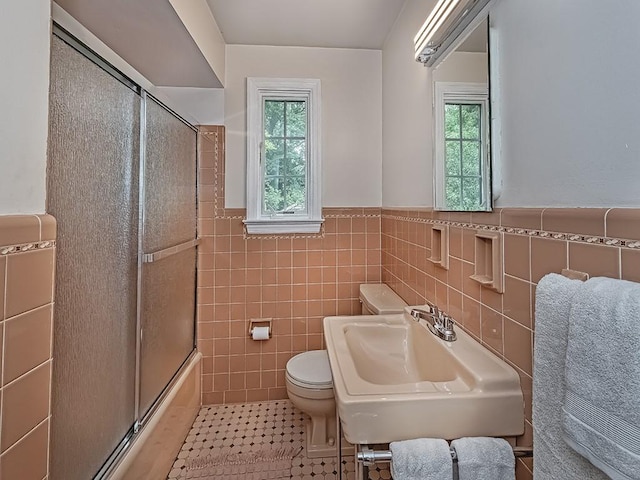 776 Elm Spring Rd, Mt Lebanon, PA 15243 - bathroom with tile walls, plenty of natural light, a wainscoted wall, shower / bath combination with glass door, and tile patterned floors