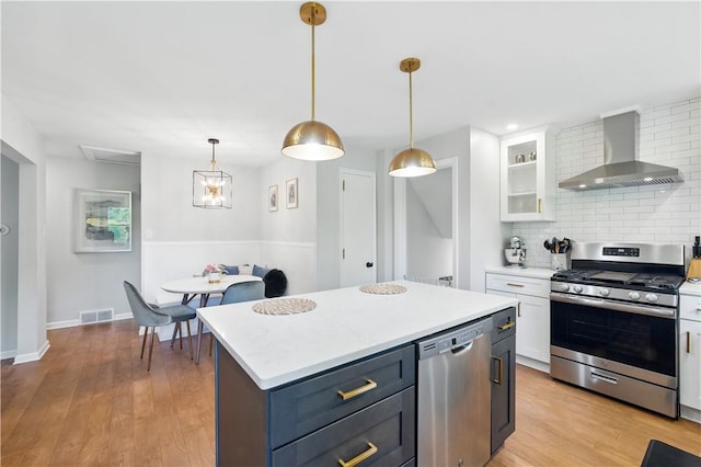 110 Simon Ave, Ross Twp, PA 15237 - kitchen with stainless steel appliances, wall chimney range hood, white cabinets, decorative backsplash, and light countertops