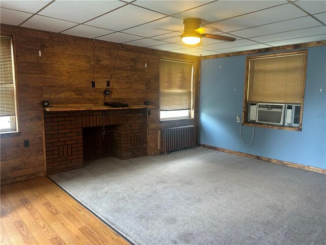 147 S 9th St, Connellsville, PA 15425 - unfurnished living room featuring radiator heating unit, cooling unit, wood walls, a fireplace, and a drop ceiling