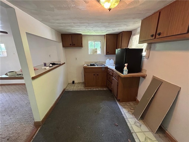19 Wickhaven Hollow Rd, Perry Twp Fay, PA 15492 - kitchen featuring a textured ceiling, light flooring, brown cabinets, light colored carpet, and freestanding refrigerator
