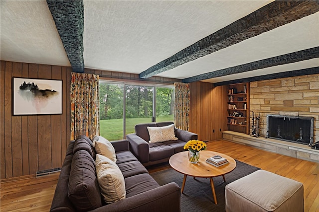 480 Herbst Manor Rd, Kennedy Twp, PA 15108 - living room with wooden walls, wood-type flooring, beam ceiling, a fireplace, and a textured ceiling