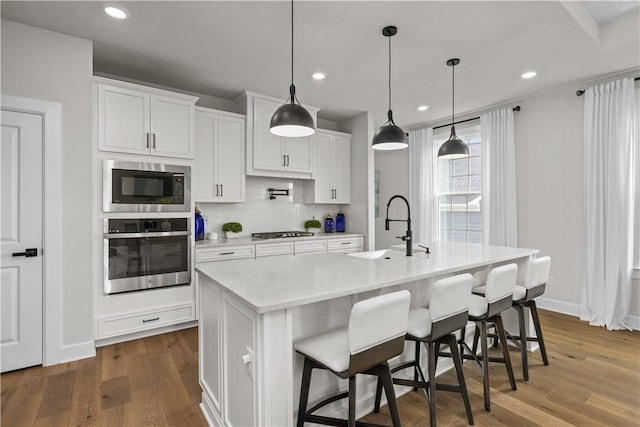 159 Heather Dr, North Strabane, PA 15317 - kitchen featuring appliances with stainless steel finishes, dark wood-style floors, an island with sink, decorative backsplash, and white cabinets