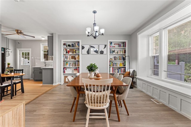 5719 Hobart St, Squirrel Hill, PA 15217 - dining room with a chandelier, light wood finished floors, a ceiling fan, and built in shelves