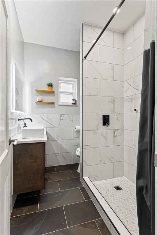 5719 Hobart St, Squirrel Hill, PA 15217 - bathroom featuring tile walls, vanity, a tile shower, tile patterned flooring, and wainscoting