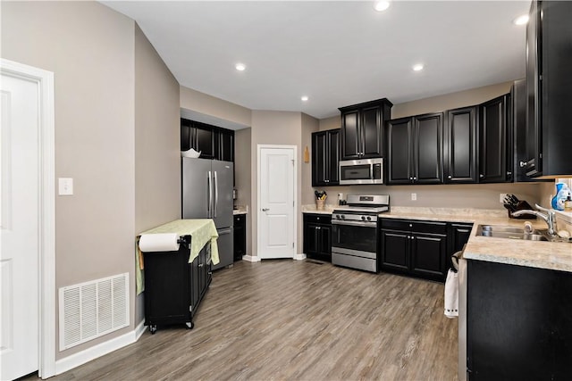 159 Horseshoe Dr, North Fayette, PA 15071 - kitchen featuring appliances with stainless steel finishes, dark cabinets, light countertops, light wood-type flooring, and recessed lighting