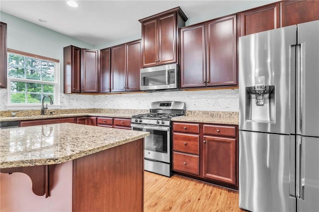 2972 Cross Creek Ct, Hampton, PA 15044 - kitchen featuring appliances with stainless steel finishes, light stone counters, light wood-type flooring, backsplash, and a kitchen breakfast bar