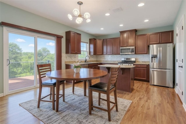 2972 Cross Creek Ct, Hampton, PA 15044 - kitchen featuring appliances with stainless steel finishes, decorative backsplash, light wood-style flooring, pendant lighting, and a kitchen island