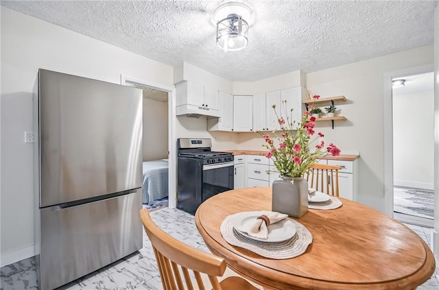 209 George St, Farrell, PA 16121 - kitchen with appliances with stainless steel finishes, under cabinet range hood, white cabinetry, light marble finish flooring, and light countertops