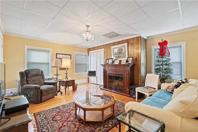 2403 Jenny Lind St, Mckeesport, PA 15132 - living area featuring crown molding, a glass covered fireplace, wood finished floors, a paneled ceiling, and a chandelier