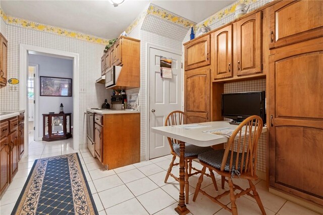 517 Keystone Dr, New Kensington, PA 15068 - kitchen featuring wallpapered walls, light countertops, light tile patterned flooring, and brown cabinets