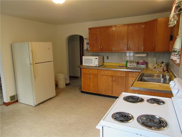 1764 Rose St, Lower Burrell, PA 15068 - kitchen featuring white appliances, arched walkways, brown cabinetry, and light flooring