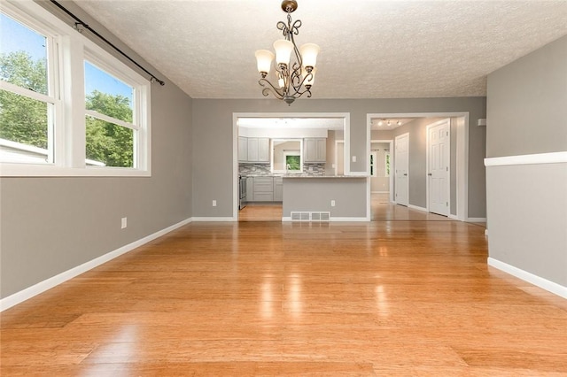 453 Falls Ave, Neshannock Twp, PA 16105 - unfurnished living room with a chandelier, a textured ceiling, and light wood finished floors