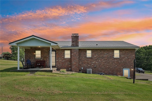 379 Airport Rd, Worthington, PA 16262 - back of house at dusk with a yard, a chimney, brick siding, and a standing seam roof