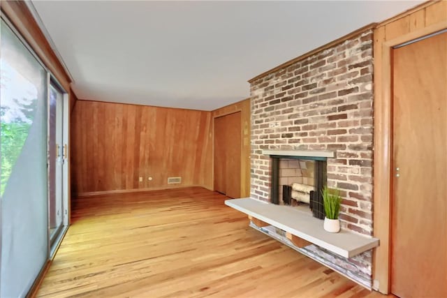 113 S Heide Ln, Peters Twp, PA 15317 - unfurnished living room with light wood-style flooring, a brick fireplace, and wood walls