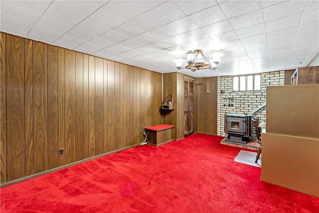463 Thomas St, Monroeville, PA 15146 - spare room featuring a wood stove, carpet flooring, wood walls, and a chandelier