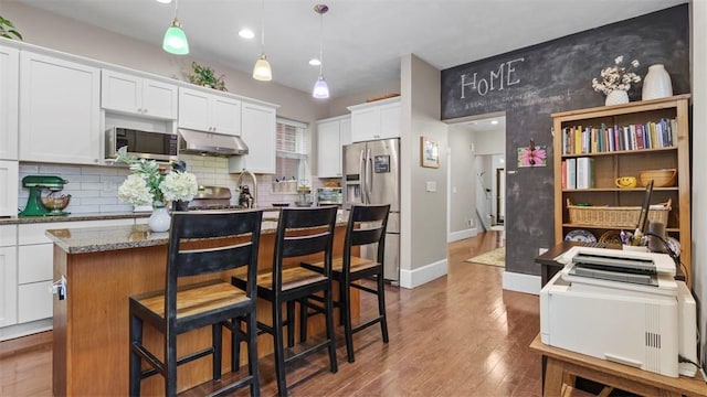 422 S Lang Ave, Point Breeze, PA 15208 - kitchen with under cabinet range hood, stainless steel appliances, a center island, white cabinetry, and wood finished floors