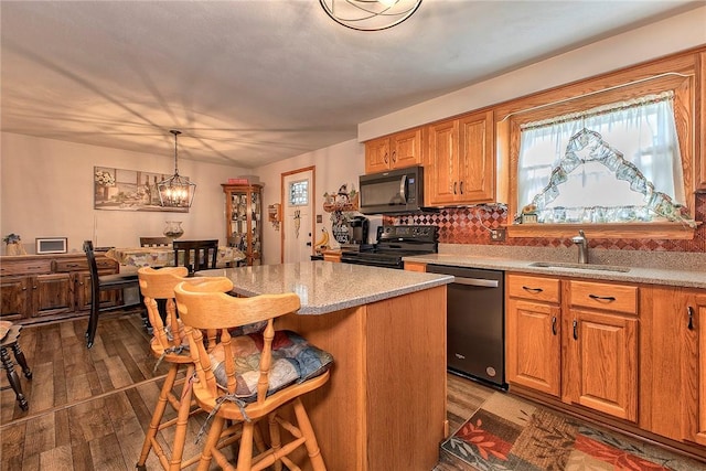 354 Moween Rd, Loyalhanna, PA 15681 - kitchen featuring black appliances, a kitchen breakfast bar, wood finished floors, decorative backsplash, and pendant lighting