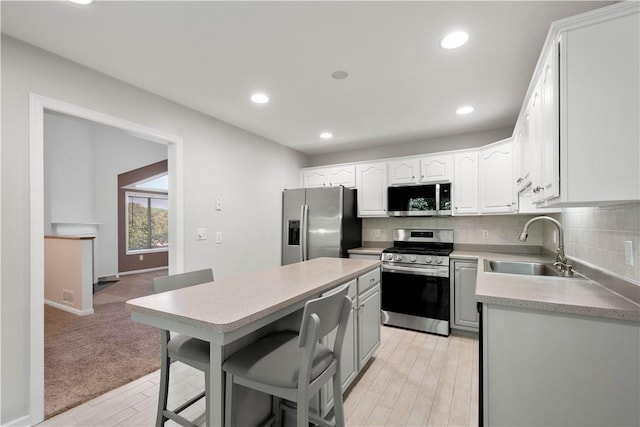 9404 Sundance Dr, South Fayette, PA 15017 - kitchen featuring appliances with stainless steel finishes, a kitchen breakfast bar, decorative backsplash, a kitchen island, and light wood-style floors