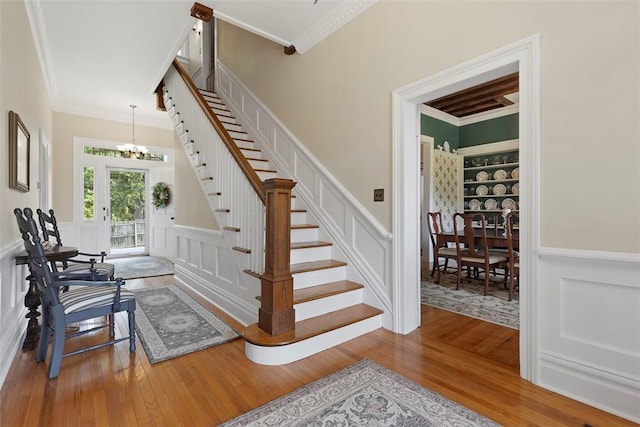 899 Old Thorn Run Rd, Moon/Crescent Twp, PA 15108 - staircase featuring a chandelier, crown molding, a decorative wall, wood finished floors, and wainscoting