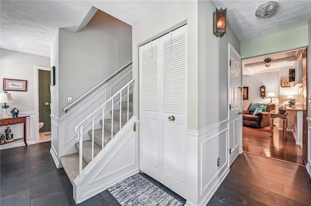 4735 Pine Cone Dr, Hermitage, PA 16148 - staircase featuring a textured ceiling, wainscoting, and a decorative wall