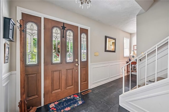 4735 Pine Cone Dr, Hermitage, PA 16148 - foyer entrance featuring a decorative wall, stairs, wainscoting, a textured ceiling, and dark stone finish floors