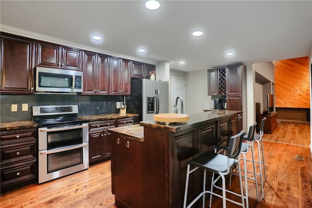 1259 Lakevue Dr, Penn Twp, PA 16001 - kitchen with appliances with stainless steel finishes, a center island with sink, a breakfast bar, light wood-style floors, and tasteful backsplash