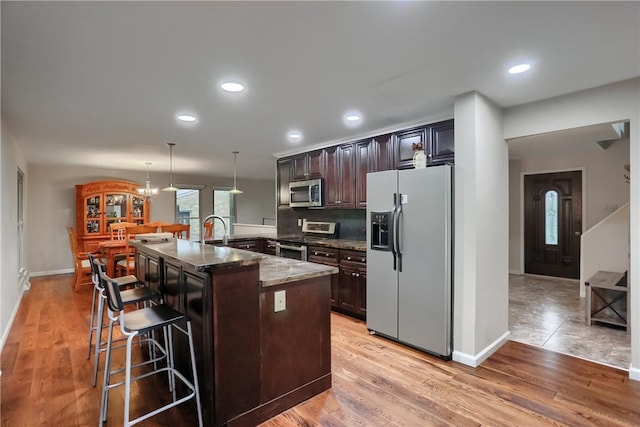1259 Lakevue Dr, Penn Twp, PA 16001 - kitchen featuring appliances with stainless steel finishes, a kitchen breakfast bar, dark stone countertops, decorative light fixtures, and dark brown cabinets