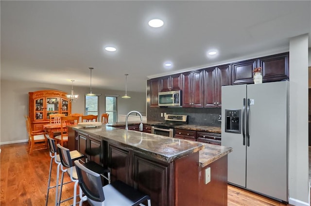 1259 Lakevue Dr, Penn Twp, PA 16001 - kitchen featuring appliances with stainless steel finishes, a kitchen breakfast bar, pendant lighting, light wood-type flooring, and dark stone counters