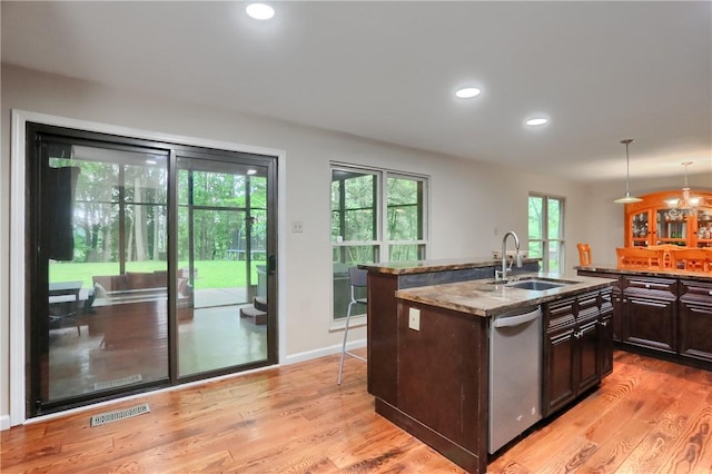 1259 Lakevue Dr, Penn Twp, PA 16001 - kitchen featuring stainless steel dishwasher, a center island with sink, dark stone counters, light wood finished floors, and dark brown cabinetry